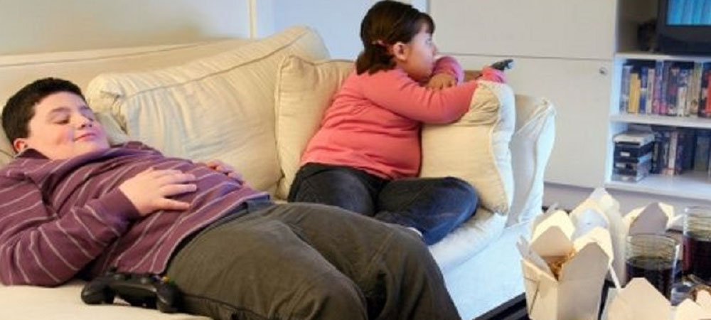 bambino obesi che stanno sul divano a guardare la televisione